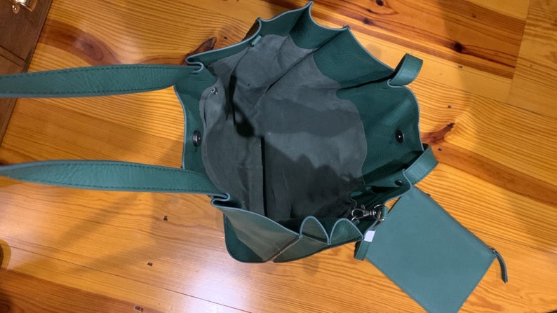 Puede incluir: Vista abierta de un bolso tote verde azulado con una bolsa a juego. El bolso tote tiene dos asas y un cierre de cord&oacute;n. La bolsa tiene cierre de cremallera y una correa peque&ntilde;a. La bolsa est&aacute; hecha de un material suave.