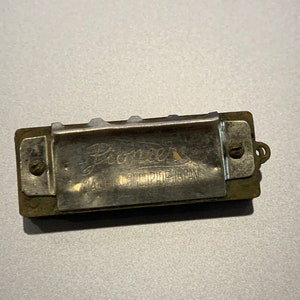 May include: A silver harmonica with the text "Premier Made in Occupied Japan" on the front.