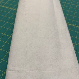 May include: A white, rectangular, fabric sheet folded in half. The sheet has a slightly textured surface.