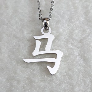 May include: A silver necklace with a pendant featuring the Chinese character for "horse".