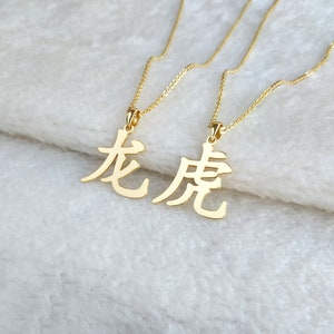 May include: Two gold necklaces with Chinese character pendants. The characters are "龙" and "虎", which translate to "dragon" and "tiger".