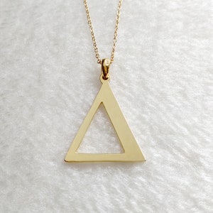 Peut inclure: Un collier avec un pendentif en forme de triangle en or et une cha&icirc;ne d&eacute;licate. Le triangle est creux et a une finition lisse et polie.