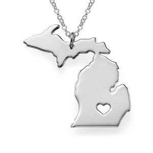May include: A silver necklace with a pendant shaped like the state of Michigan. The pendant has a small heart cut out of it.