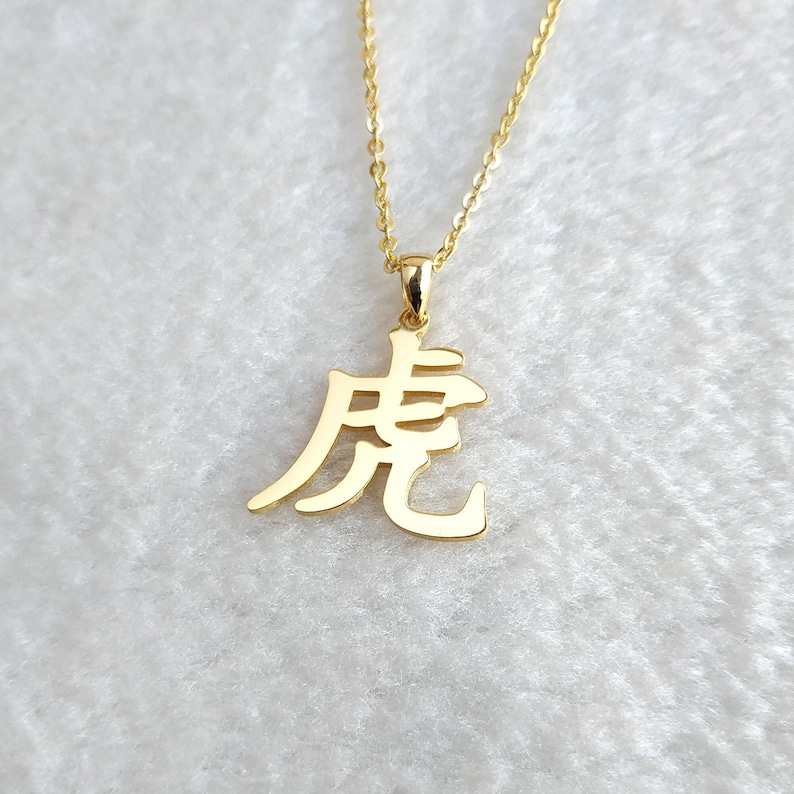 May include: Gold necklace with a pendant featuring the Chinese character for "dragon".
