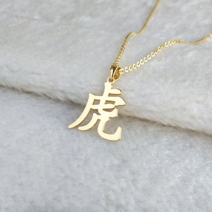 May include: Gold necklace with a pendant featuring the Chinese character for "dragon".