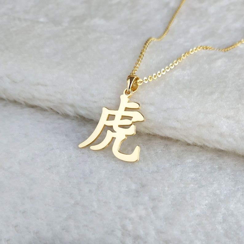 May include: Gold necklace with a pendant featuring the Chinese character for "dragon".