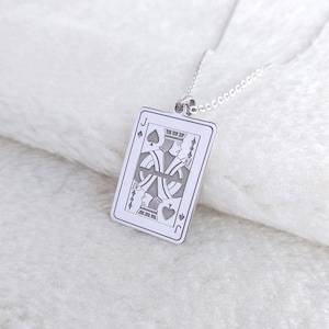 May include: A silver pendant necklace with a detailed engraving of the Jack of Spades playing card. The rectangular pendant with rounded corners hangs from a delicate chain. The card design includes the spade symbol and the letter "J".