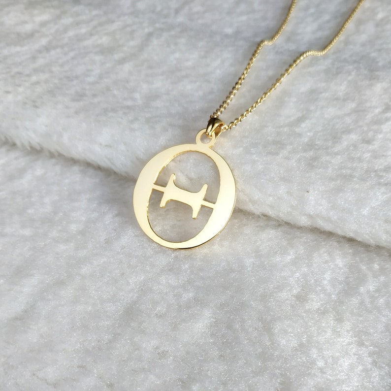 Peut inclure: Un collier en or avec un pendentif en forme de lettre "O" avec un "H" plus petit d&eacute;coup&eacute; &agrave; l'int&eacute;rieur.