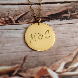 May include: Gold necklace with a round pendant engraved with the initials "M&C".