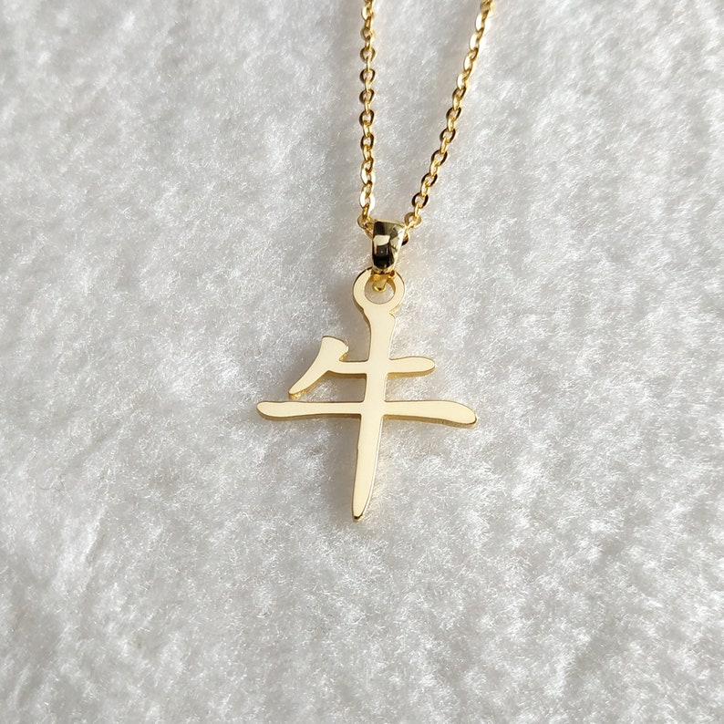 May include: Gold necklace with a pendant featuring the Chinese character for "ox" or "cow".