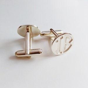 Puede incluir: Un par de gemelos de plata con un dise&ntilde;o de monograma. Los gemelos son redondos y tienen un acabado liso y pulido.