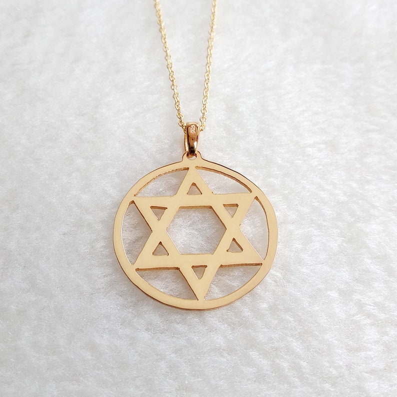 May include: A gold necklace with a pendant in the shape of a Star of David. The pendant is a circle with a six-pointed star cut out of the center.
