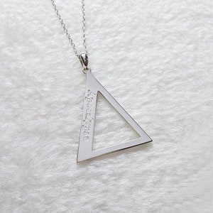 Peut inclure: Un collier en argent avec un pendentif en forme de triangle sur lequel est inscrit "Apocalypse".