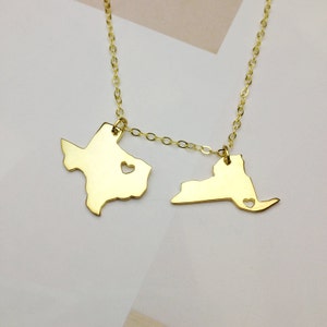 May include: Gold necklace with two state charms, Texas and New York, each with a small heart cutout.