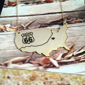 May include: Gold necklace featuring a map of the United States with a Route 66 sign and a small heart in the center.
