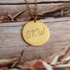 May include: Gold necklace with a round pendant engraved with the initials "SKW".