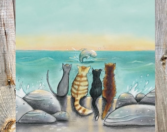 Könnte beinhalten: Vier Katzen sitzen auf Felsen am Meer und beobachten einen Fisch, der aus dem Wasser springt. Die Katzen sind eine graue Tabby, eine braune Tabby, eine schwarze Katze und eine dreifarbige Katze.