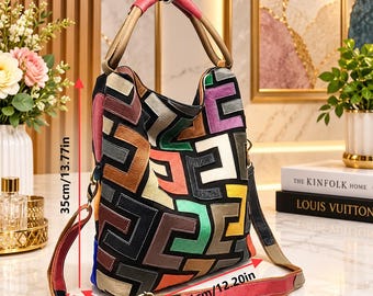 Puede incluir: Un bolso hobo multicolor con un patrón geométrico de patchwork en negro, marrón, morado, verde, amarillo y naranja. El bolso tiene un asa rosa y beige, una correa de hombro extraíble y mide 35 cm por 31 cm por 10 cm.