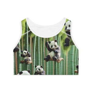 May include: White crop top featuring a repeating pattern of pandas in a bamboo forest. The pandas are black and white, some swinging on swings. The background is a green bamboo forest.