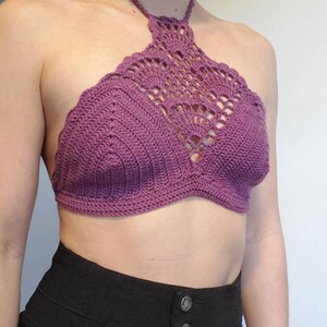 Pu&ograve; includere: Un top halter color porpora lavorato a uncinetto con un motivo delicato. Il top &egrave; corto e ha uno stile a halter.