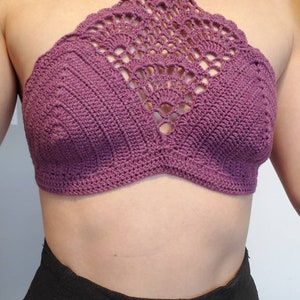 Pu&ograve; includere: Un top halter in crochet viola con un design delicato e intricato. Il top &egrave; senza maniche e ha un'alta scollatura.
