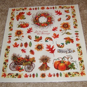 May include: A square sheet with autumn-themed illustrations. It features pumpkins, sunflowers, fall leaves, and a wreath. Text includes "Let Us Count Our Blessings" and "Thank You". The border has a decorative leaf pattern.