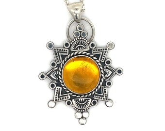 May include: A silver pendant necklace with a large, round, yellow amber stone set in a detailed, star-shaped design.
