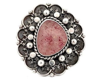 May include: A silver ring with a pink stone set in a detailed floral design.