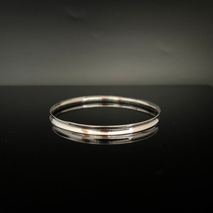 May include: A silver bangle bracelet with a smooth, polished finish.