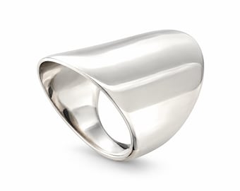 Puede incluir: Un anillo de plata pulida con una banda ancha, lisa y curva que se estrecha hacia la abertura del dedo. La superficie metálica es altamente reflectante, creando una forma elegante y continua con una silueta redondeada y asimétrica.