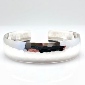 Peut inclure: Un bracelet manchette en argent martelé. Le bracelet est lisse et brillant, avec une forme légèrement arrondie.