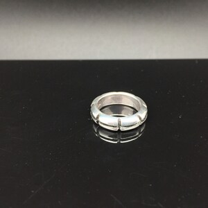 May include: A silver ring with a textured band. The band has a series of small, evenly spaced cuts around the circumference.