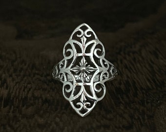 May include: A silver filigree ring with a geometric design. The ring is made of intricate swirls and curves, creating a delicate and elegant look.