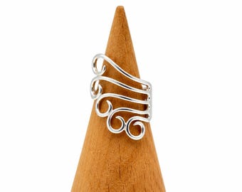 May include: A silver-colored ring featuring a series of four stacked, open-work wire loops that curve upward and outward. The metal has a polished, reflective finish, and the design consists of interconnected, swirling lines that form a wing-like shape.