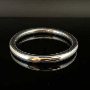 Puede incluir: Un brazalete de plata con un acabado liso y pulido.