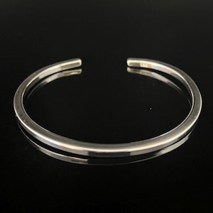 May include: A simple silver bangle bracelet with a smooth, polished finish.