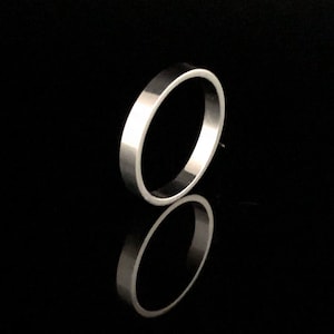 May include: A silver ring with a smooth, polished finish. The ring is simple and elegant, with a classic design.