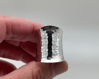 Può includere: Un anello in metallo martellato argentato con una fascia larga.