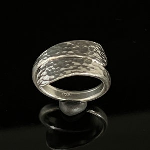 May include: A silver ring with a hammered texture. The ring is made of two bands that are twisted together. The ring is marked with the number "925" on the inside.
