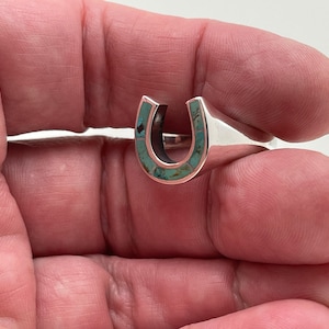 May include: Sterling silver ring with a turquoise horseshoe design.