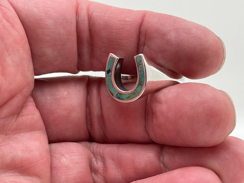 May include: Sterling silver ring with a turquoise horseshoe design.
