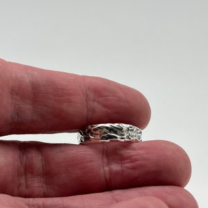 Puede incluir: Un anillo de plata con una superficie texturizada.