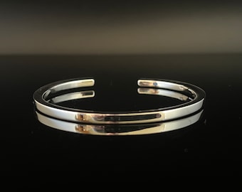 Op de afbeelding: Een zilveren armband met een gladde, gepolijste afwerking.