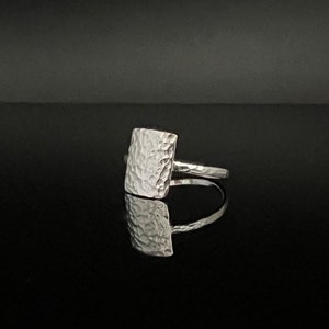 May include: A silver ring with a hammered square-shaped top.