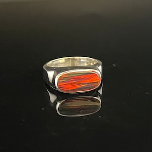 May include: A silver ring with a rectangular red, orange, and green gemstone.