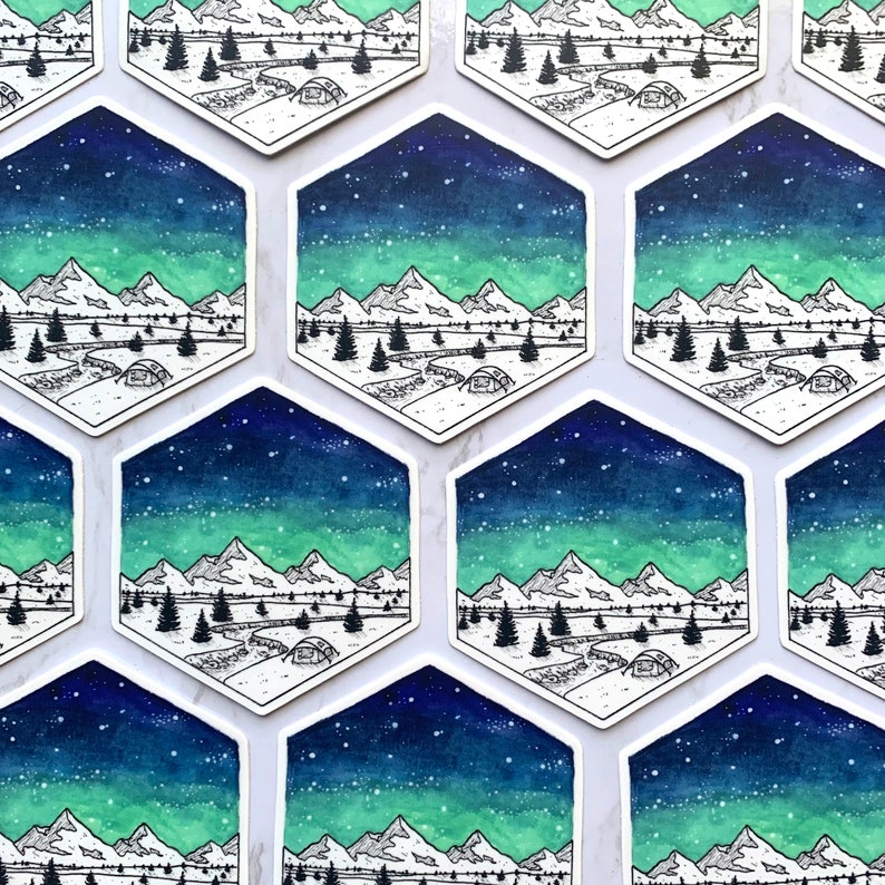 May include: A set of nine hexagonal stickers featuring a watercolor illustration of a mountain range under a starry sky with a green aurora borealis. The illustration is in black and white with a blue and green watercolor wash.