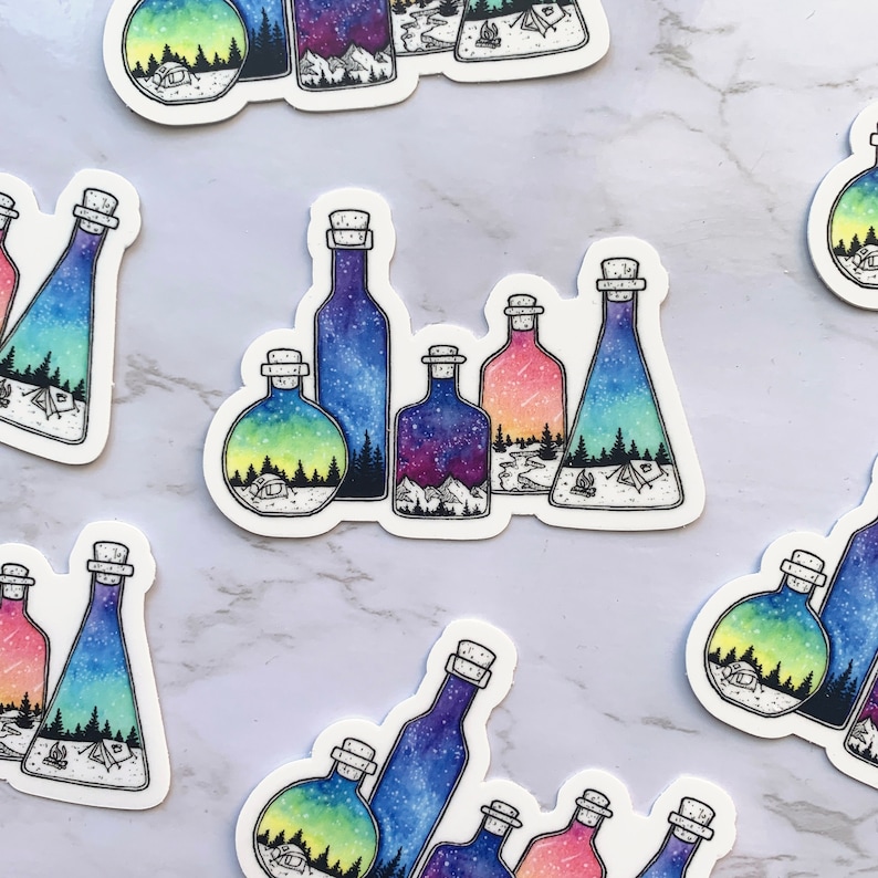 May include: Six glass bottles with cork stoppers, each containing a different watercolor scene of a starry night sky, a mountain range, a forest, and a campfire. The bottles are arranged in a row on a white marble surface.