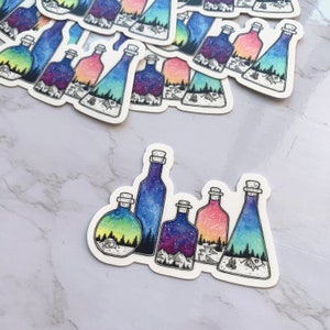 May include: Five glass bottles with cork stoppers, each containing a different watercolor scene of a starry night sky, mountains, and a forest. The bottles are arranged in a row on a white background.