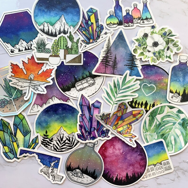 K&ouml;nnte beinhalten: Eine Sammlung bunter Aufkleber mit verschiedenen Designs, darunter Kristalle, Berge, Blumen und ein Van. Die Aufkleber sind im Aquarell-Stil mit einem sternenklaren Nachthimmel als Hintergrund gemalt.