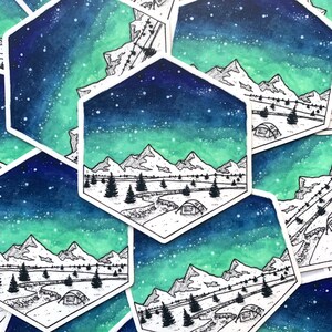 May include: A hexagonal sticker with a watercolor background of a starry night sky with a green aurora borealis. The sticker features a black line drawing of a mountain range with a river and a tent in the foreground.